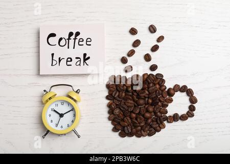 Tasse aus Bohnen, Karte mit Phrase Kaffeepause und Wecker auf weißem Holztisch, flach liegend Stockfoto