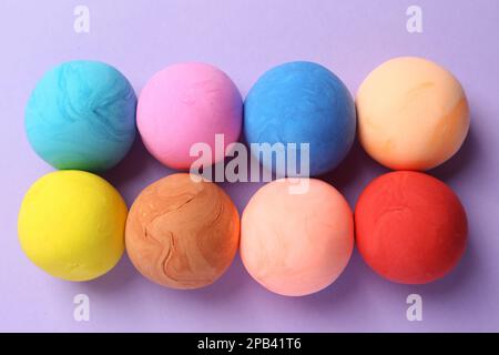 Verschiedene Farben spielen Teig auf violettem Hintergrund, flach liegend Stockfoto