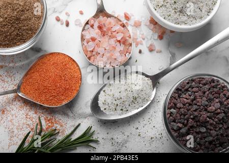 Flache Liegezusammensetzung mit verschiedenen Salzsorten auf weißem Marmortisch Stockfoto