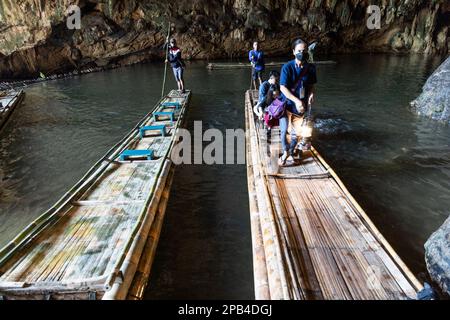 MAE HONG SON, THAILAND, 10. März 2023: Ein ortskundiger Shan-Reiseleiter führt Touristen am Tham Nam Loc mit traditionellen Laternen auf Bambusflößen im Inneren des Stockfoto