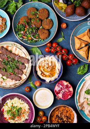 Im Nahen und Mittleren Osten oder arabische Gerichte und verschiedene Meze, Beton rustikales Hintergrund. Fleisch Döner, Falafel, Baba ghanoush, muhammara, Hummus, sambusak, Reis, Stockfoto