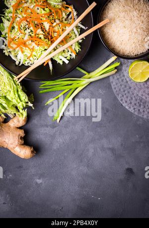 Zutaten für die Zubereitung des vietnamesischen Abendessens: Reispapier, Reis, napakohl, Ingwer, grüne Zwiebeln, Salat. Asiatische Kochzutaten. Draufsicht. Ich mache einen Wettbewerb Stockfoto