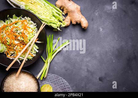 Zutaten für die Zubereitung des vietnamesischen Abendessens: Reispapier, Reis, napakohl, Ingwer, grüne Zwiebeln, Salat. Asiatische Kochzutaten. Draufsicht. Ich mache einen Wettbewerb Stockfoto