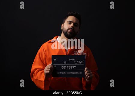 Gefangener mit Fahndungsbrieftafel auf schwarzem Hintergrund Stockfoto