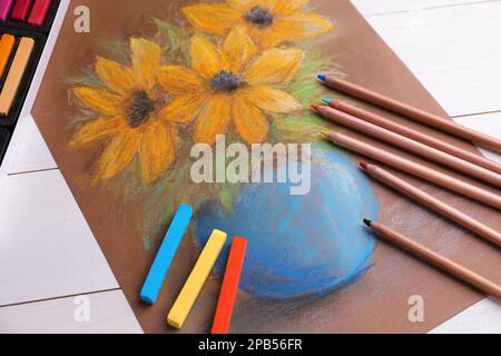 Farbenfrohe Kreidepastelltöne, Bleistifte und wunderschöne Blumenmalerei auf einem weißen Holztisch, Blick über die Kulisse Stockfoto