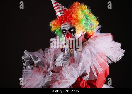 Ein furchteinflößender Clown auf schwarzem Hintergrund. Halloween-Party-Kostüm Stockfoto