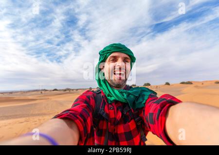 Glücklicher männlicher Tourist Selfie auf Sanddünen in der afrikanischen Wüste, Sahara Nationalpark - Influencer Reise-Blogger genießt Reise, während sich selbst p Stockfoto