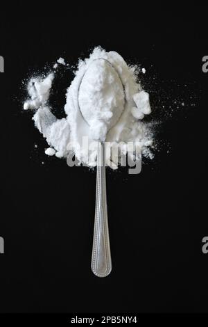 Löffel Backpulver auf schwarzem Hintergrund, flach liegend Stockfoto