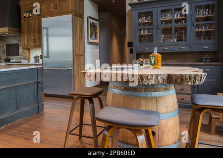 Schränke aus gefärbtem Kirschholz, Whiskey Barrel Bar mit Barhockern und antikes Holzkiefernbuffet in der Küche im Hybridholzrahmen Haus. Stockfoto