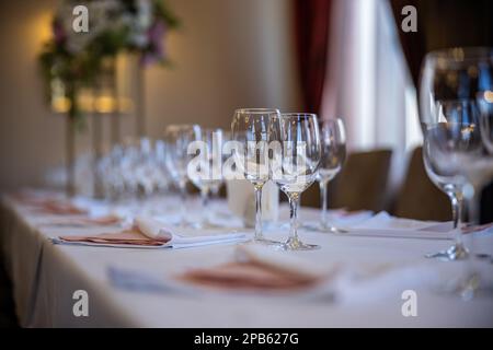 Wunderschön angelegte Tische mit Gläsern und Geräten am Morgen im Restaurant, das für eine Hochzeit eingerichtet wurde. Hochwertiges Foto Stockfoto