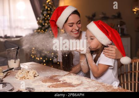 Mutter und ihre süße kleine Tochter haben Spaß, während sie in der Küche Teig für Weihnachtskekse machen Stockfoto