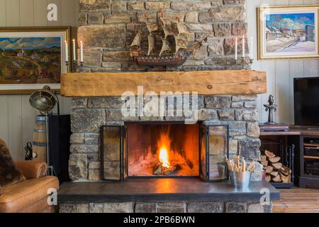 Natürlicher Stein Holz brennender Kamin im Wohnzimmer im Hybridholzrahmen Haus. Stockfoto