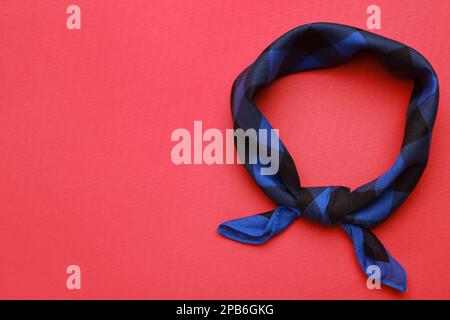 Gefliestes blaues Bandana mit Karomuster auf rotem Hintergrund, Draufsicht. Platz für Text Stockfoto