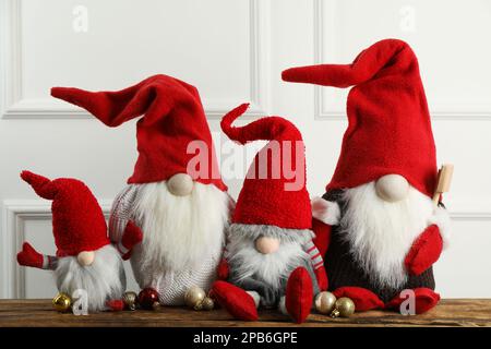 Viele niedliche Weihnachtszwerge und festliche Bälle auf einem Holztisch Stockfoto