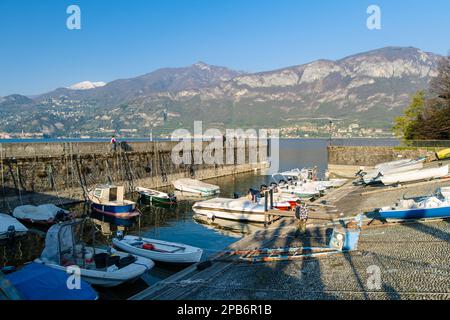 BELAGGIO, ITALIEN - APRIL 2022: Yachten und Fischerboote, die im Hafen von Bellagio, einer Stadt am Ufer des Comer Sees, anlegen. Charmante Lage mit typisch Stockfoto