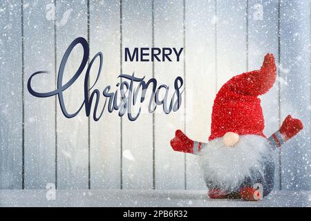 Frohe Weihnachten! Süßer Zwerg auf dem Tisch vor weißem Holzhintergrund Stockfoto