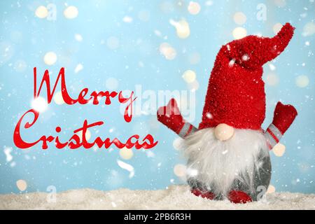 Frohe Weihnachten! Süßer Weihnachtszwerg auf Schnee vor verschwommenen festlichen Lichtern, Bokeh-Effekt Stockfoto