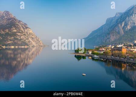 Neblige Sonnenaufgang-Stadtlandschaft von Lecco am Frühlingstag. Malerische Uferpromenade der Stadt Lecco zwischen dem berühmten Comer See und dem malerischen Bergamo A. Stockfoto