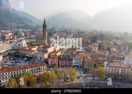 Neblige Sonnenaufgang-Stadtlandschaft von Lecco am Frühlingstag. Malerische Uferpromenade der Stadt Lecco zwischen dem berühmten Comer See und dem malerischen Bergamo A. Stockfoto