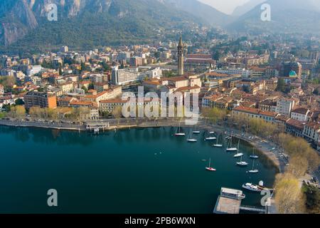 Neblige Sonnenaufgang-Stadtlandschaft von Lecco am Frühlingstag. Malerische Uferpromenade der Stadt Lecco zwischen dem berühmten Comer See und dem malerischen Bergamo A. Stockfoto