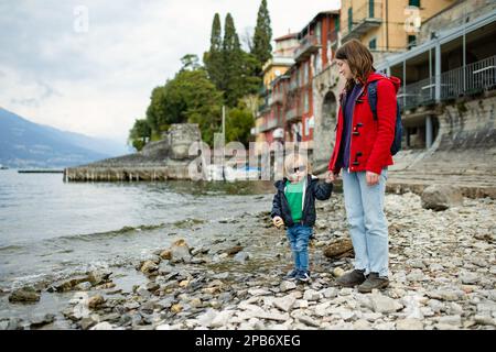 Mutter und ihr kleiner Sohn füttern Enten in Varenna, einer der malerischsten Städte am Ufer des Comer Sees. Charmante Lage mit typischem Flair Stockfoto