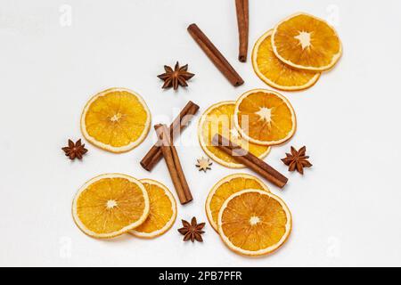 Zimtstäbchen, Sternanis und orangefarbene Chips auf weißem Hintergrund. Flach verlegt Stockfoto