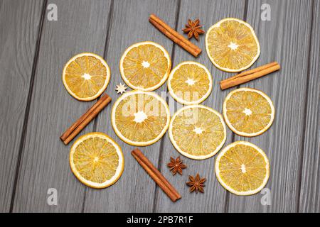 Sternanis, Zimtstangen und trockene orangefarbene Scheiben auf Holzhintergrund. Flach verlegt Stockfoto