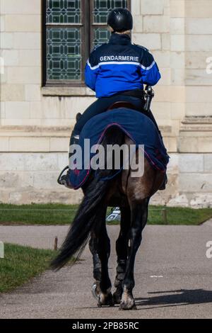 Chambord, Frankreich. 25. Februar 2023. Französischer Gendarm auf einem Pferd, von hinten gesehen, mit Inschrift Gendarme auf seiner Jacke Stockfoto