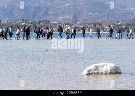 12. März 2023: Manerba del Garda, Brescia, Italien 12. März, Dürre in norditalien Menschen gehen von Punta Belvedere nach Isola dei Conigli in einem Teil des Gardasees, der aufgrund der schweren Dürre ungewöhnlich trocken ist (Bild: © Matteo Biatta/ZUMA Press Wire) REDAKTIONELLE VERWENDUNG! Nicht für den kommerziellen GEBRAUCH! Stockfoto