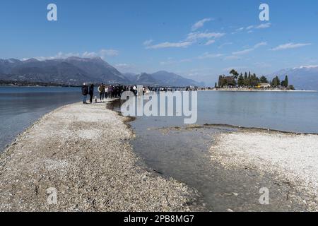 12. März 2023: Manerba del Garda, Brescia, Italien 12. März, Dürre in norditalien Menschen gehen von Punta Belvedere nach Isola dei Conigli in einem Teil des Gardasees, der aufgrund der schweren Dürre ungewöhnlich trocken ist (Bild: © Matteo Biatta/ZUMA Press Wire) REDAKTIONELLE VERWENDUNG! Nicht für den kommerziellen GEBRAUCH! Stockfoto