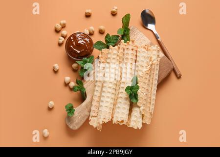 Gehen Sie an Bord mit köstlichen Waffeln, gekochter Kondensmilch, Minze und Haselnüssen auf orangefarbenem Hintergrund Stockfoto