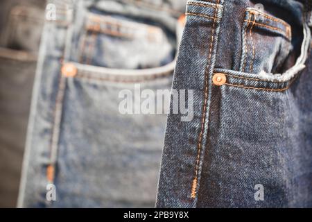 Viele Jeans, die an der Spielbank hängen. Eine Reihe Hosen Jeans, die im Schrank hängen, Konzept des Kaufs, Verkaufs, Einkaufs und Jeans Mode Stockfoto