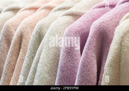 Modische Winterkleidung auf Kleiderständer - farbenfroher Kleiderschrank. Nahaufnahme Regenbogenfarbe Auswahl an trendigen Kleidungsstücken für Damen an Kleiderbügeln im Ladenschrank oder Stockfoto