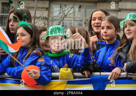 London, Großbritannien. 12. März 2023. Eine Gruppe junger Teilnehmer auf einem der Schwimmwagen winkt den Zuschauern zu. Die jährlich stattfindende St. Patrick's Day Parade führt durch das Zentrum von London, um die irische Gemeinde und irische Kultur und das irische Erbe mit Teilnehmern in Kostümen, Marschkapellen, Pracht und vielem mehr zu feiern, die von Zuschauern entlang der Strecke beobachtet werden. Kredit: Imageplotter/Alamy Live News Stockfoto