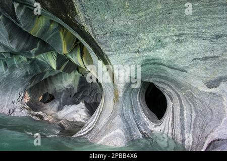 Erodierte Oberflächen und Löcher in den Marmorhöhlen mit Reflexionen vom türkisfarbenen Wasser des Lago General Carrera, Patagonien Stockfoto