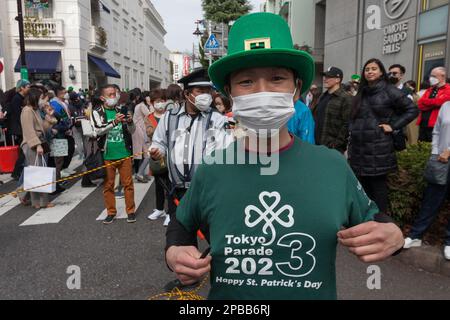 Tokio, Japan. 12. März 2023. Ein Beamter kontrolliert die Menge bei der Parade zum Saint Patrick's Day 28. in Omotesando, Tokio. Die Parade ist die größte und älteste St. Patrick's Day Veranstaltung in Asien und kehrte dieses Jahr nach einer 3-jährigen Pause durch den Coronavirus zurück. Es war ein zweitägiges 'I love Ireland' Festival mit Essen, Musik und anderen kulturellen Veranstaltungen im nahe gelegenen Yoyogi Park. (Foto: Damon Coulter/SOPA Images/Sipa USA) Guthaben: SIPA USA/Alamy Live News Stockfoto