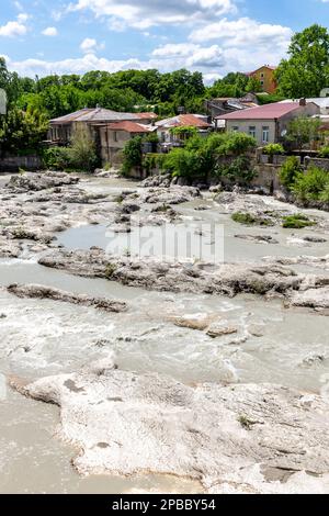 Rioni River in Kutaisi, Landschaftsblick mit weißen Steinen und Wohnhäusern am Flussufer, Blick von der Weißen Brücke, Sommer, Georgia. Stockfoto
