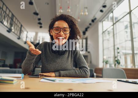 Eine Frau führt ein Videokonferenz, die online mit einem Kollegen spricht, der am Schreibtisch sitzt Stockfoto