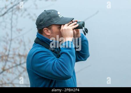 Ein Mann, der durch ein Fernglas schaut und Vögel beobachtet Stockfoto