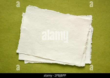 Kleines Blatt leeres, weißes Khadi-Papier gegen grünes Lappen-Papier Stockfoto