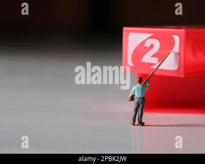 Eine Nahaufnahme von Miniaturfiguren von Arbeitern, die Objekte nach Zahlen färben. Farbfoto Konzept. Stockfoto