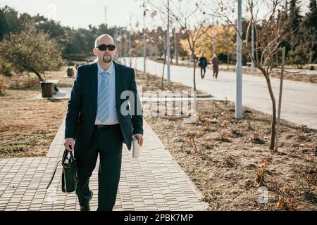 Reifer Unternehmer trinkt Kaffee im Herbstpark. Ruhestand für Führungskräfte im Stadtpark. Stockfoto