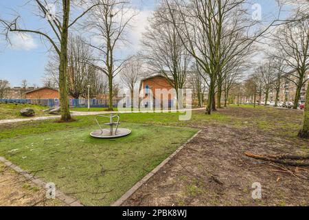 Ein leerer Spielplatz mitten in einem Wohngebiet, wo keine Leute oder Kinder auf dem Gras und den Bäumen spielen Stockfoto