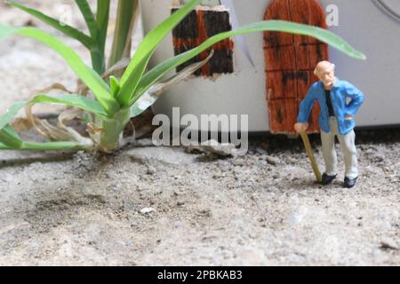 Miniaturfigur eines Großvaters, der vor dem Haus wartet. Stockfoto