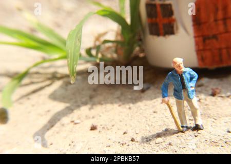 Miniaturfigur eines Großvaters, der vor dem Haus wartet. Stockfoto