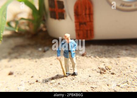 Miniaturfigur eines Großvaters, der vor dem Haus wartet. Stockfoto