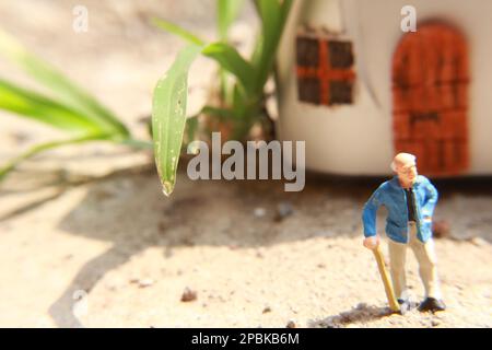 Miniaturfigur eines Großvaters, der vor dem Haus wartet. Stockfoto