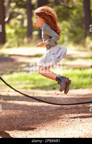 In Glück springen. Ein junges rothaariges Mädchen, das über ein Seil springt. Stockfoto