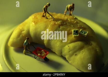 Miniaturfiguren von Arbeitern, die gemeinsam Getreide bewegen. Stockfoto