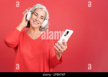 Reife Frau, die mit einem Handy Musik hört Stockfoto